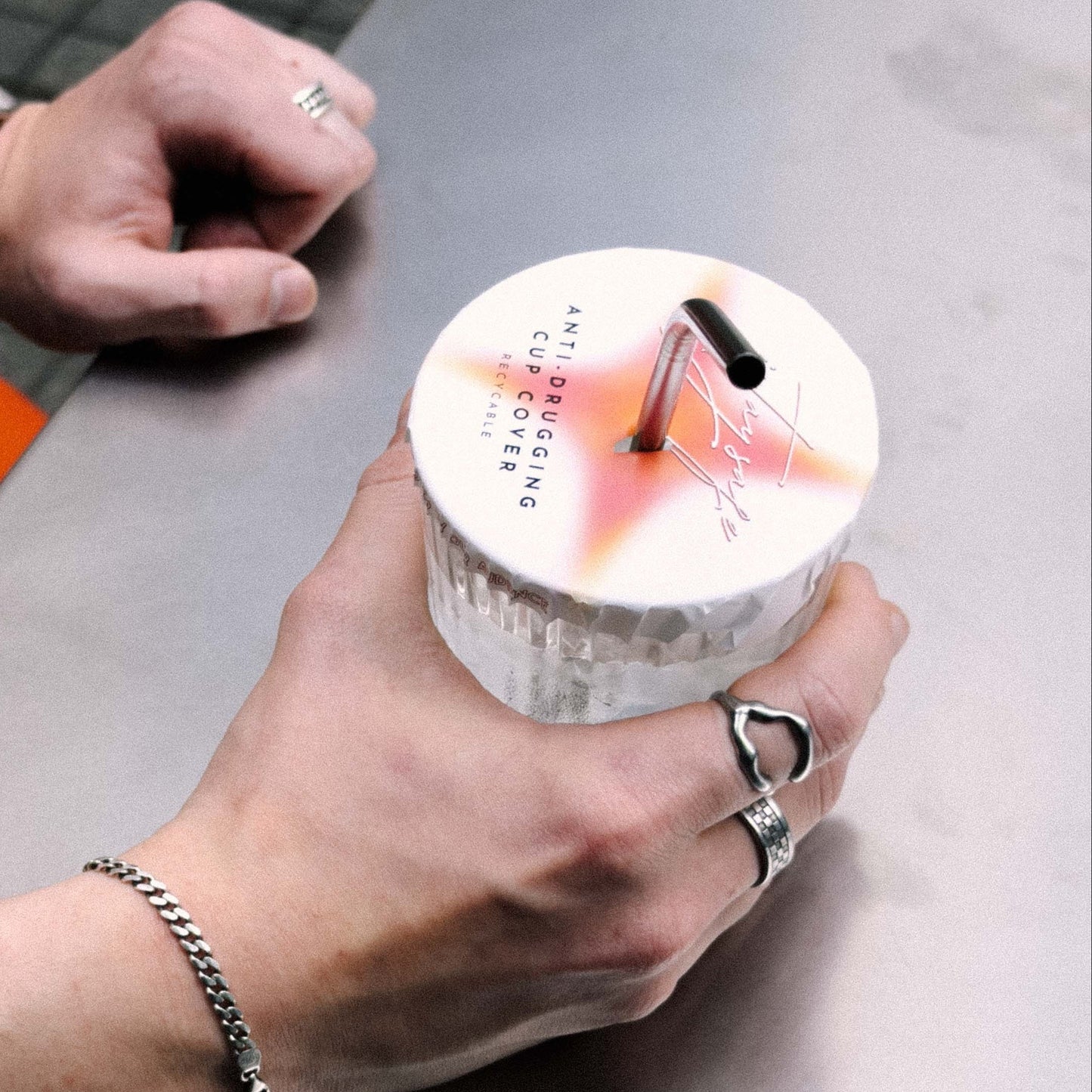 Person holding a drink with a ISTAYSAFE cover on it.