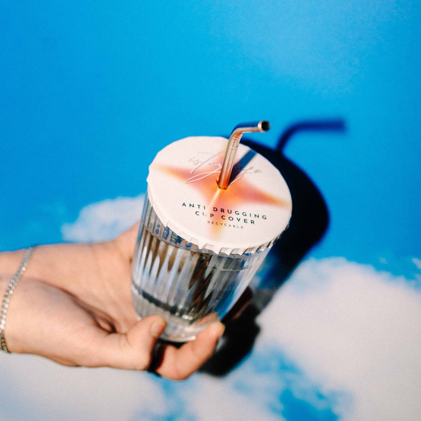 Hand holding a cup with a ISTAYSAFE cover on it, with blue sky background